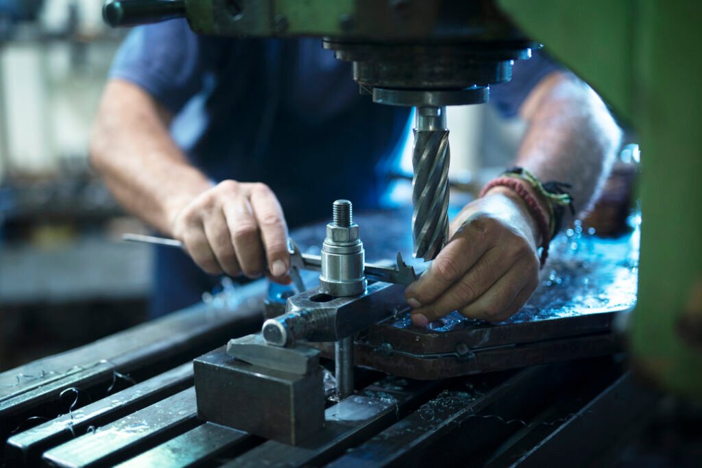 Worker operating industrial machine in metal workshop.